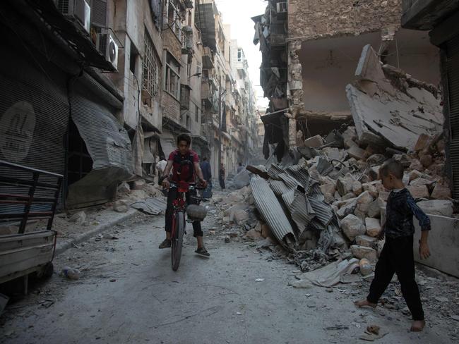 Syrians walk through the rubble following an airstrike on the regime-controlled neighbourdhood of Karm al-Jabal on September 18. Picture: AFP