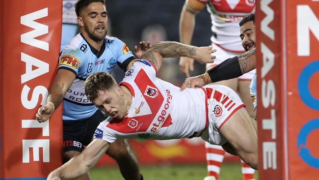 Cameron McInnes of the Dragons scores despite pressure from William Kennedy and Andrew Fifita of the Sharks during the Round 5 NRL match between the St. George Illawarra Dragons and the Cronulla Sutherland Sharks at Campbelltown Stadium in Sydney, Sunday, June 14, 2020. (AAP Image/Craig Golding) NO ARCHIVING, EDITORIAL USE ONLY