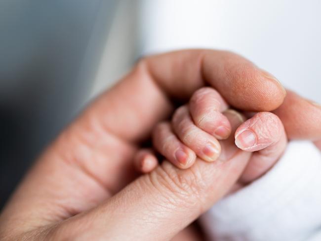 Hand of newborn baby who has just been born holding the finger of his father's hand.CREDIT ISTOCK