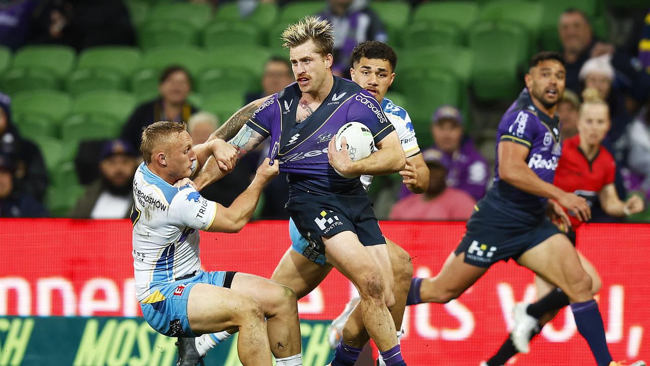 MELBOURNE, AUSTRALIA - AUGUST 05: Cameron Munster of the Storm passes the ball while being tackled by Alexander Brimson of the Titans (L) during the round 21 NRL match between the Melbourne Storm and the Gold Coast Titans at AAMI Park, on August 05, 2022, in Melbourne, Australia. (Photo by Daniel Pockett/Getty Images)