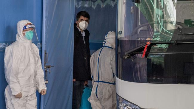 A member of the World Health Organization (WHO) team investigating the origins of the COVID-19 pandemic boards a bus following their arrival at a cordoned-off section in the international arrivals area at the airport in Wuhan. Picture: Nicolas Asfouri/AFP