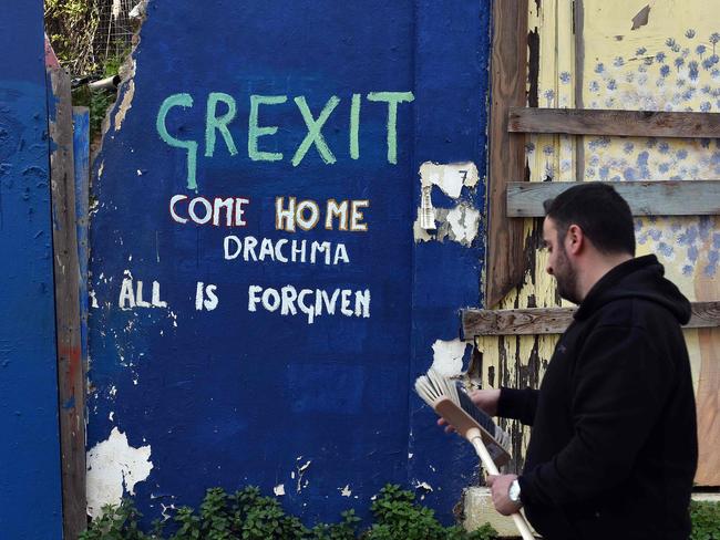 A man walks past a slogan on a wall in central Athens on February 20, 2017. Eurozone finance ministers will on February 20 seek the outline of a deal to unblock bailout cash for Greece before fraught elections across Europe endanger a quick fix. / AFP PHOTO / LOUISA GOULIAMAKI