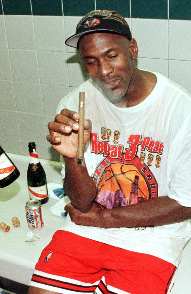 ‘Repeat 3-peat’. Michael Jordan mid-cigar and with a Bud Light beer in the Chicago Bulls’ locker room. Picture: AFP