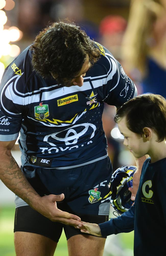 Johnathan Thurston runs onto the field with kids.