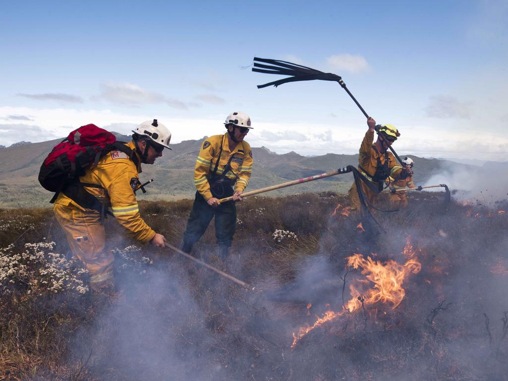 Parks and TFS firefighters smother the remains of the fire edge after aircraft water bombers saturate the area. Picture: WARREN FREY / TASMANIA FIRE SERVICE