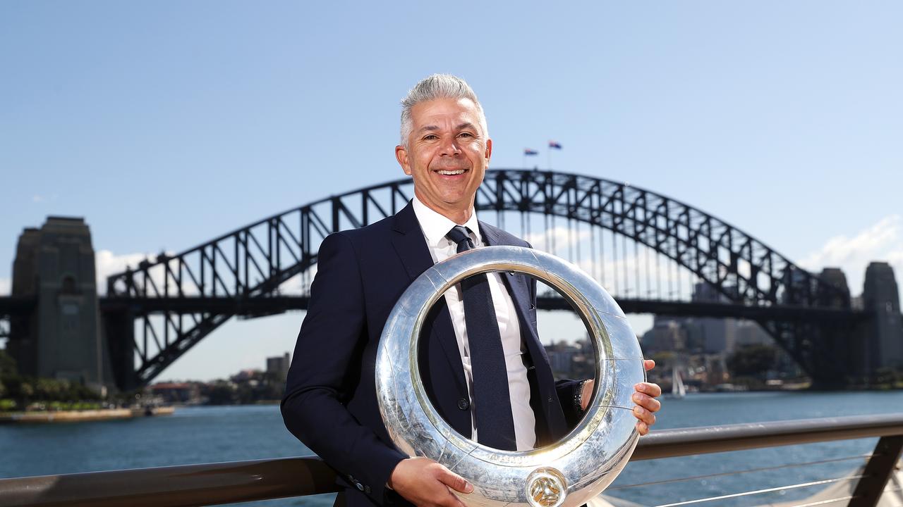 Steve Corica posing with the A-League trophy he has won as a player and coach.