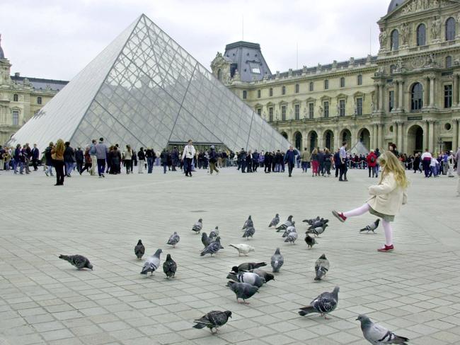 06 May 2005 : USA tourist Paris Maning (foreground right) playing with pigeons in front of the Louvre in Paris, France