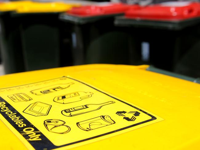 Recycling bins (yellow lids) sit with general waste bins on a nature strip in Sydney, Friday, Nov. 13, 2009. This year marks the 14th anniversary of National Recycling Week, a community education and media campaign to bring attention to recycling and minimising waste. (AAP Image/Tracey Nearmy) NO ARCHIVING