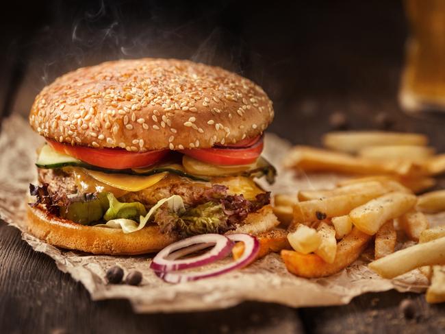 Tasty hamburger with french fries and beer on wooden table