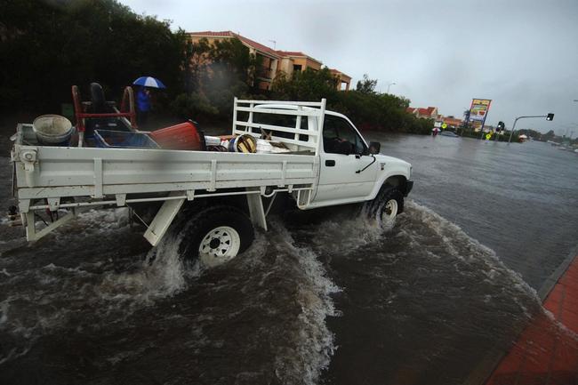 Gold Coast, June 30, 2005. Four wheel drive vehicles cross a flooded intersection at Varsity Lakes on Queensland’s Gold Coast today. Widespread flooding has hit the popular tourist area, known for its sunshine and sandy beaches, with reports of rainfall reaching 80mm per hour in some regions. (AAP Image/Tony Phillips)