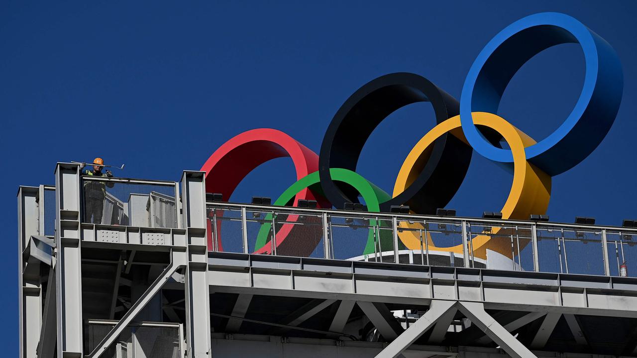 A worker paints a part of a building where the Olympic Rings are located for the Beijing 2022 Winter Olympics. Picture: AFP.