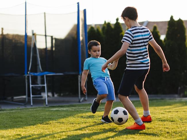 Brothers playing soccer in their backyard