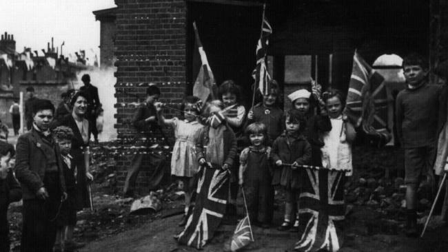 Children celebrate VE Day in Battersea, South London, surrounded by the rubble of their bombed homes.