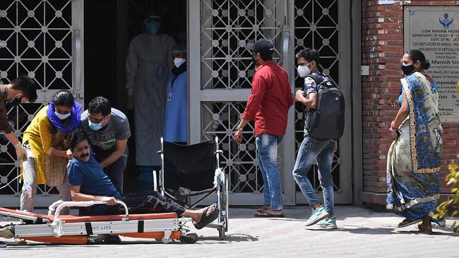 A coronavirus patient is helped by relatives outside a COVID-19 ward at a hospital in New Delhi. Picture: AFP