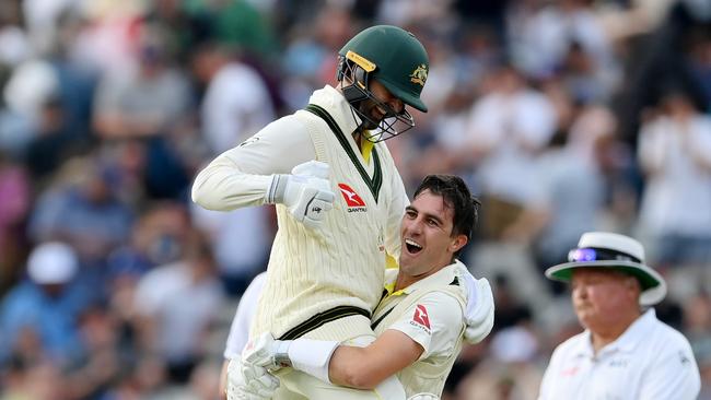 Cummins lifts Nathan Lyon in the air after hitting the winning runs in the first Ashes test.