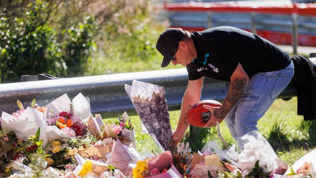 A man lays a bunch of flowers and a football at the memorial site. Picture: David Swift