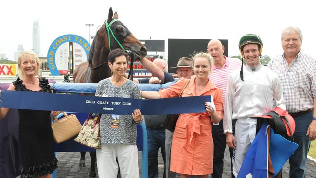 Trainer Angela Plumb (orange dress) and jockey Ryan Plumb (second from right) celebrate with Barraaj’s owners after their win at the Gold Coast. Photo: Jessica Hawkins/Trackside Photography