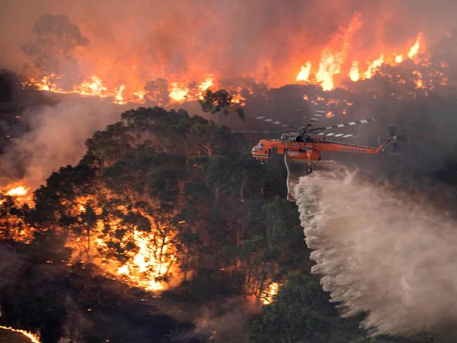 TOPSHOT - A handout photo taken and received on December 31, 2019 from the State Government of Victoria shows a helicopter fighting a bushfire near Bairnsdale in Victoria's East Gippsland region. - Thousands of holidaymakers and locals were forced to flee to beaches in fire-ravaged southeast Australia on December 31, as blazes ripped through popular tourist areas leaving no escape by land. (Photo by Handout / STATE GOVERNMENT OF VICTORIA / AFP) / RESTRICTED TO EDITORIAL USE - MANDATORY CREDIT "AFP PHOTO / STATE GOVERNMENT OF VICTORIA" - NO MARKETING NO ADVERTISING CAMPAIGNS - DISTRIBUTED AS A SERVICE TO CLIENTS