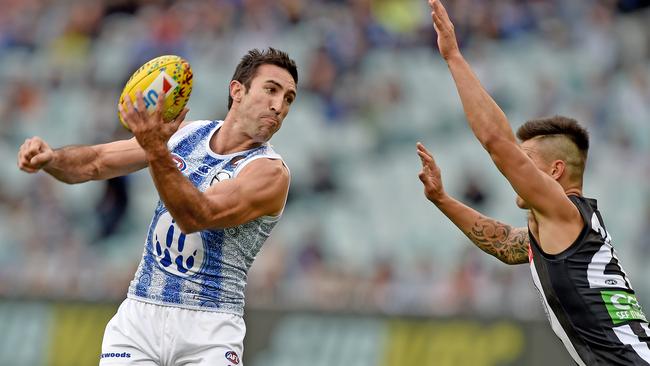 Michael Firrito of the Kangaroos passes the ball over Marley Williams of the Magpies in a game at the MCG in 2015. (AAP Image/Joe Castro)