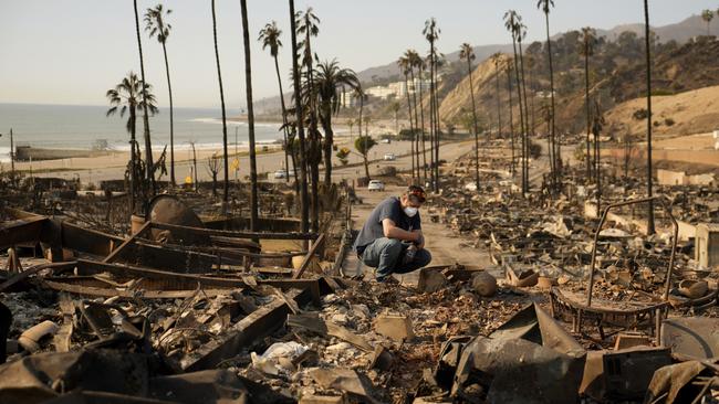 Kevin Marshall sifts through his mother's fire-ravaged property in the Pacific Palisades neighbourhood of Los Angeles on Saturday. Picture: AP Photo/John Locher