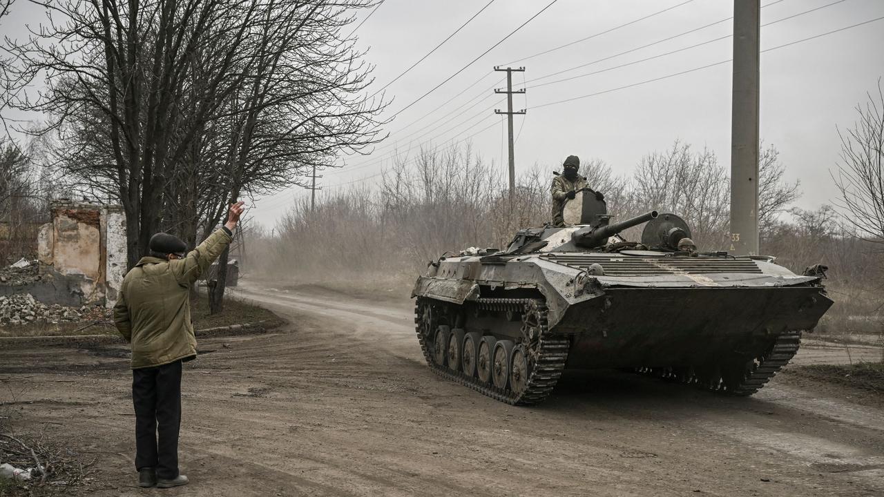 A local resident waves at a Ukrainian infantry fighting vehicle BMP-1 on their way to the frontline, near Bakhmut, eastern Ukraine, on March 17, 2023, amid the Russian invasion of Ukraine. Picture: Aris Messinis / AFP