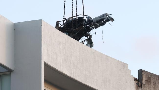 A large crane lifts the wreckage of a Robinson R44 helicopter off the roof top of the Double Tree Hilton hotel into a skip bin, before lowering it to the Cairns Esplanade. The chopper was stolen from Nautilus Aviation and crashed onto the roof at about 1:50am on Monday. Picture: Brendan Radke