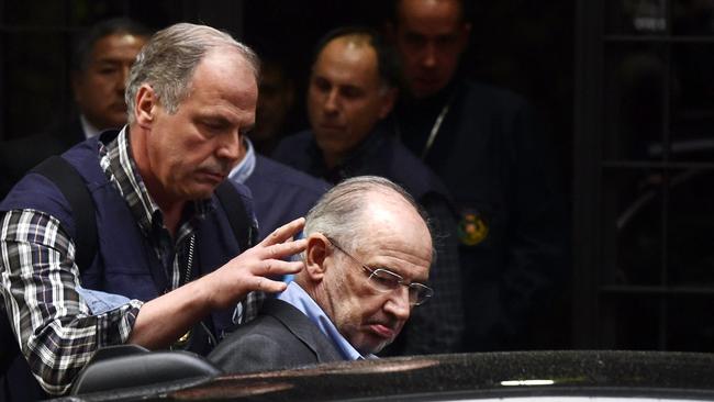 Police assist Rodrigo Rato into a car outside his home in Madrid. Picture: AFP