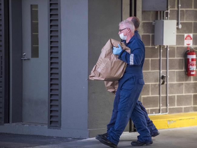 Police walk out of a Docklands apartment block with large bags. Picture: Jason Edwards