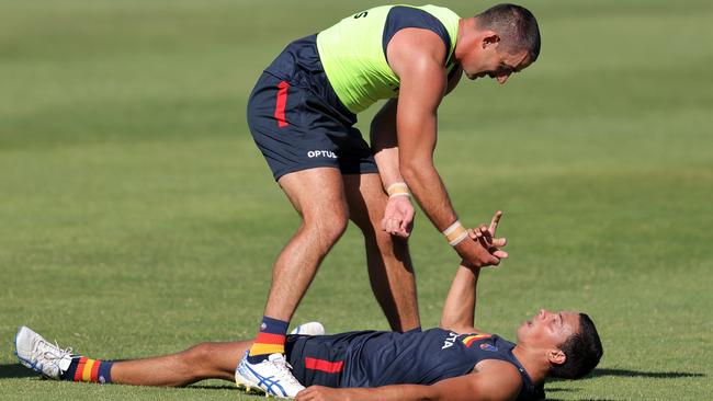 Taylor Walker offers Ben Davis a hand during a pre-season training session.