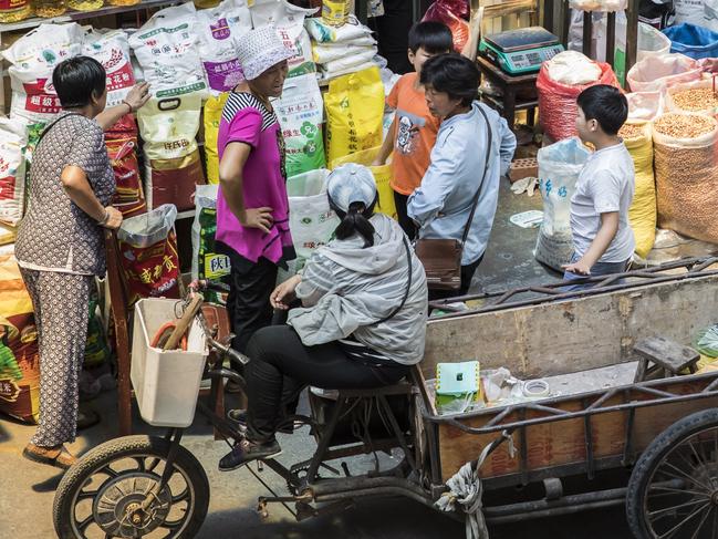 Customers with carts gather round a grain store at a wholesale market in Shanghai, China, on Friday, July 13, 2018. China is scheduled to release gross domestic product (GDP) figures on July 16. Photographer: Qilai Shen/Bloomberg