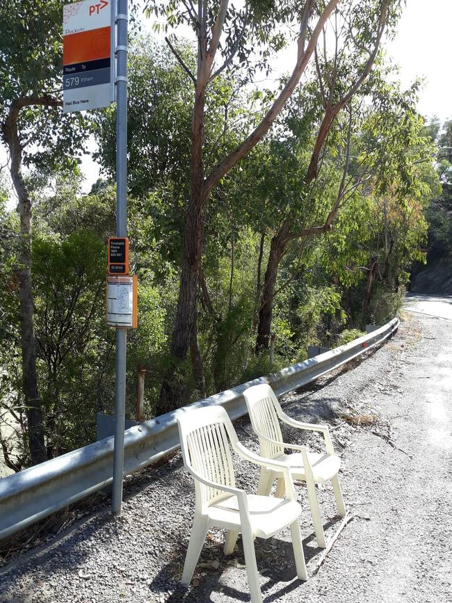 Two backyard chairs grace a basic bus stop. 