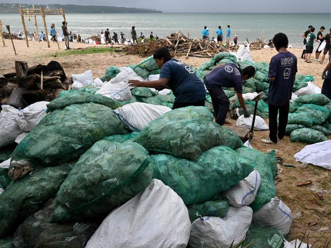 Participants and volunteers remove plastic waste and other garbage washed ashore at a beach in Kedonganan Badung regency, Indonesia's Bali island on January 4, 2025. (Photo by SONNY TUMBELAKA / AFP)