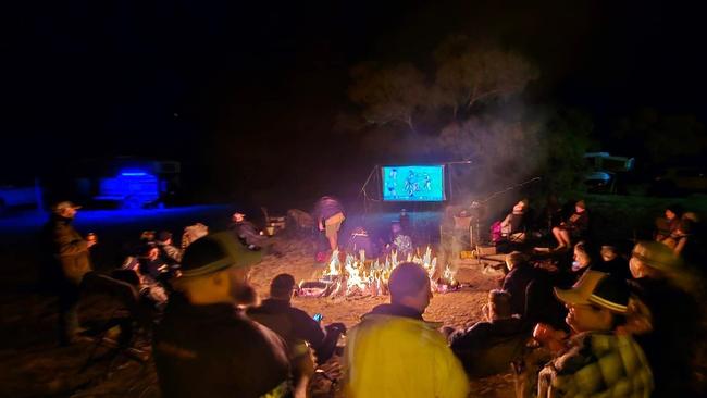 Campers gather around a fire and a TV in the middle of the outback to watch the Women's State of Origin Game 3. Picture: Ed Banks