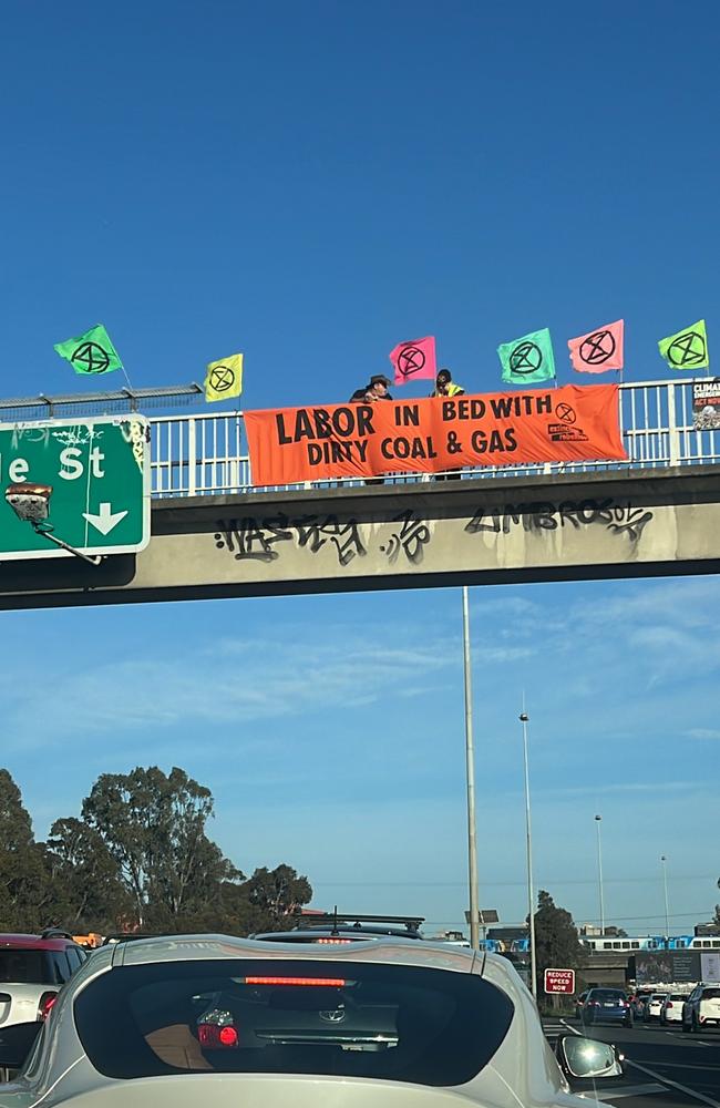 Extinction Rebellion protesters take over the footbridge above the busy Eastern Freeway near the Hoddle Street exit on Wednesday morning. Photo: Gemma Scerri