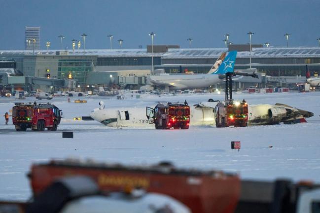 A Delta Air Lines plane sits on its back after crashing upon landing at Toronto Pearson Airport in Toronto, Ontario