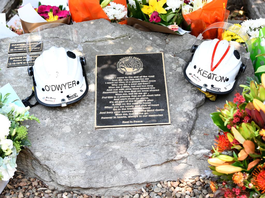 Flowers and the helmets of volunteer firefighters Andrew O'Dwyer and Geoffrey Keaton are seen at a memorial at the Horsley Park Rural Fire Brigade. Picture: Bianca De Marchi/AAP