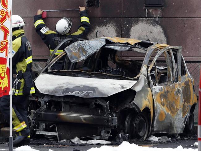 Firefighters investigate the scene where two cars caught on fire at a parking lot in Utsunomiya, north of Tokyo Sunday, Oct. 23, 2016. Police are investigating two apparent blasts, one at the parking lot and the other at a nearby public park, that happened back-to- back and left one person dead. (Yukie Nishizawa/Kyodo News via AP)