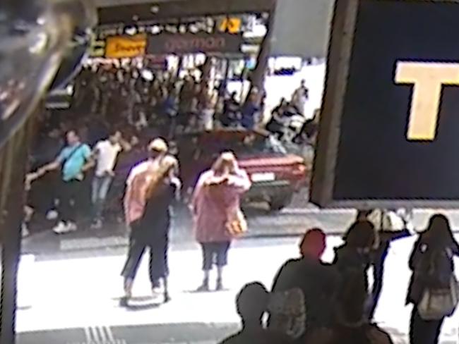 Pedestrians rush to clear a path for the car as it flies down a Swanston St footpath.