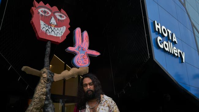 Artist Ramesh Mario Nithiyendran with his piece at the entrance to the HOTA Gallery. Photo: Alex Chomciz.