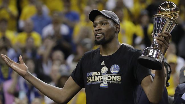 Golden State Warriors forward Kevin Durant gestures as he holds the NBA Finals MVP Trophy.