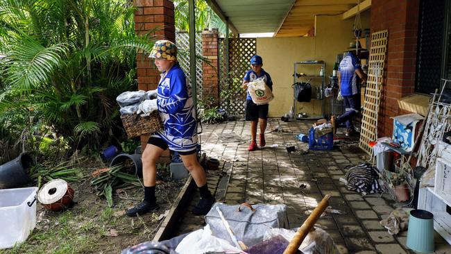 Jake Westmore, 10, and Maliq Wray, 10, of the Brothers Leagues Club help clean up a property that was flooded at Holloways Beach. Picture: Brendan Radke