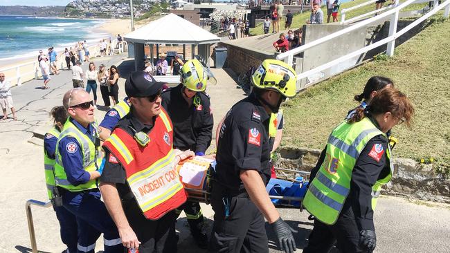 One of the occupants of the car is taken to an ambulance at Bar Beach. Picture by Peter Lorimer