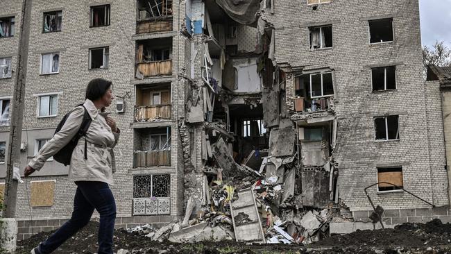TOPSHOT - A woman walks by a destroyed apartment building in Bakhmut in the eastern Ukranian region of Donbass on May 22, 2022, amid Russian invasion of Ukraine. (Photo by ARIS MESSINIS / AFP)