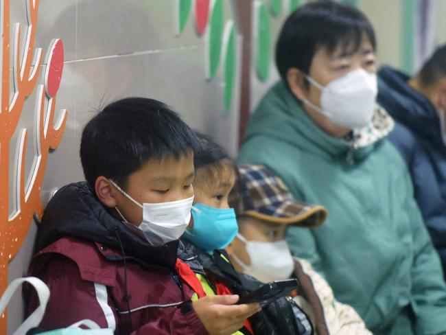 Masked children, accompanied by adults, wait to be seen by medical staff at the pediatric department of a hospital in Hangzhou, eastern China's Zhejiang province, on January 6, 2025. Beijing has acknowledged a surge in cases of the flu-like human metapneumovirus (HMPV), especially among children, and attributed this to a seasonal spike. (Photo by AFP) / China OUT