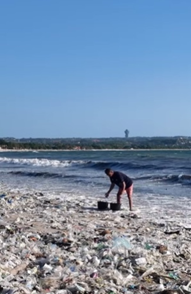 A man can be seen picking up the mounds of rubbish washed up on a beach. Picture: Instagram/nusabali_com
