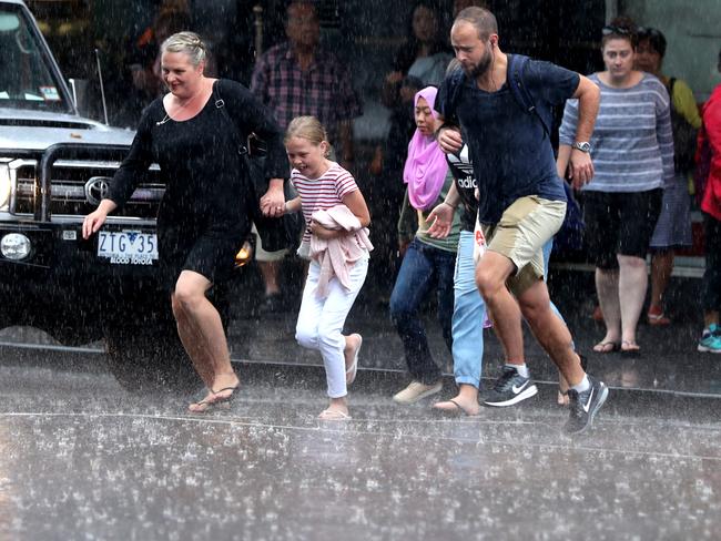 Pedestrians do their best to avoid puddles as they dash across the street in Melbourne on Tuesday. Picture Alex Coppel.