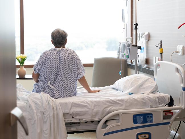 The unrecognizable female patient sits alone on her hospital bed while she waits for her nurse. Picture: Getty Images