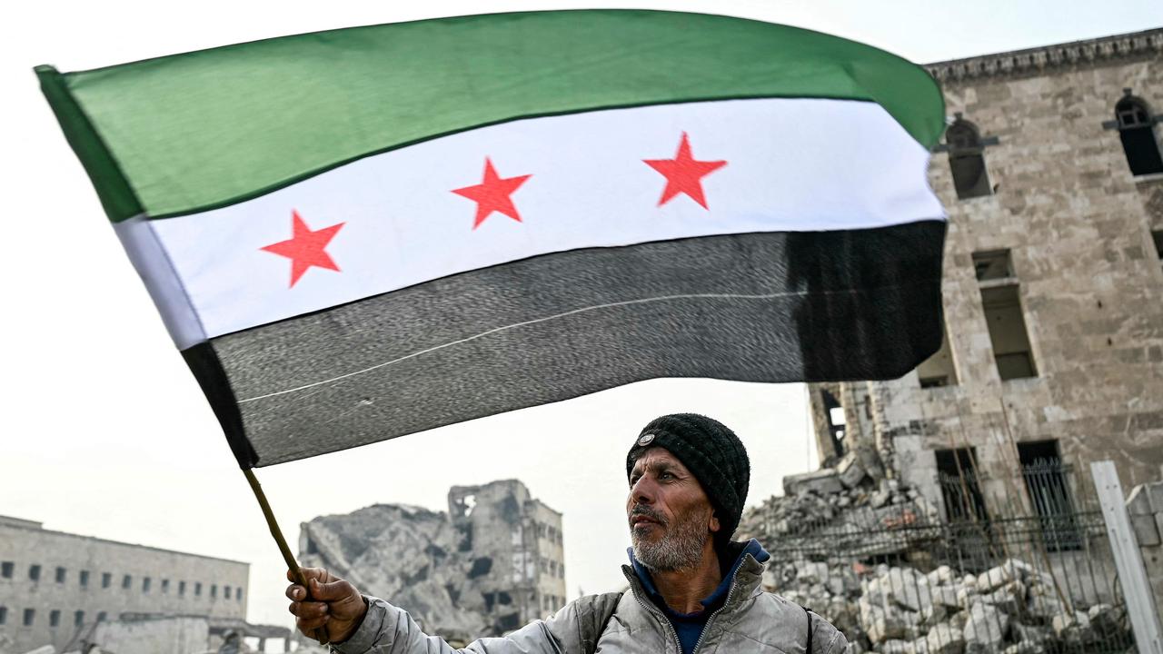 =A man waves a Syrian opposition flag at the Citadel of Aleppo in northern Syria on December 11, 2024. Picture: Ozan Kose/AFP