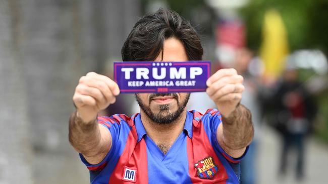 A man holds out a Trump bumper sticker as hundreds of people gather to protest the lockdown despite shelter-in-place rules still being in effect in California. Picture: AFP