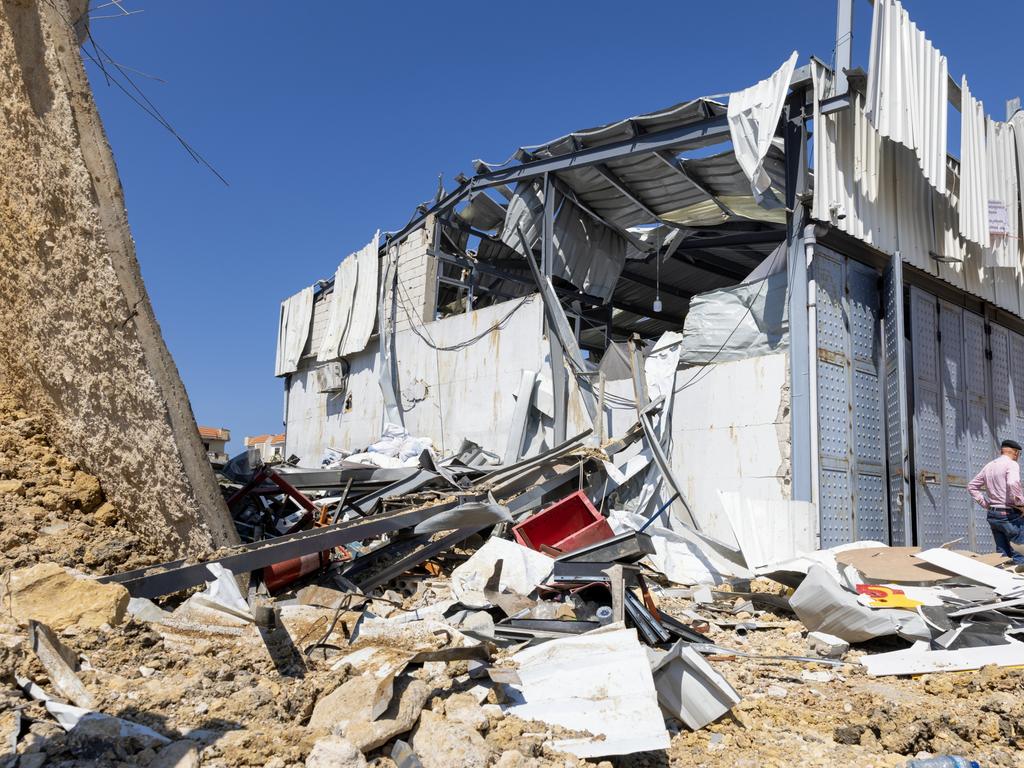 People exam the destruction after an early morning Israeli airstrike hit a vehicle mechanic shop in Jiyeh, Lebanon.